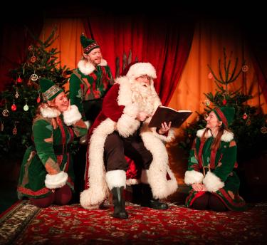 Father Christmas reading a book with his Elves